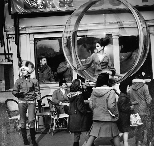 Fashion model floating in a bubble in front of a Paris cafe